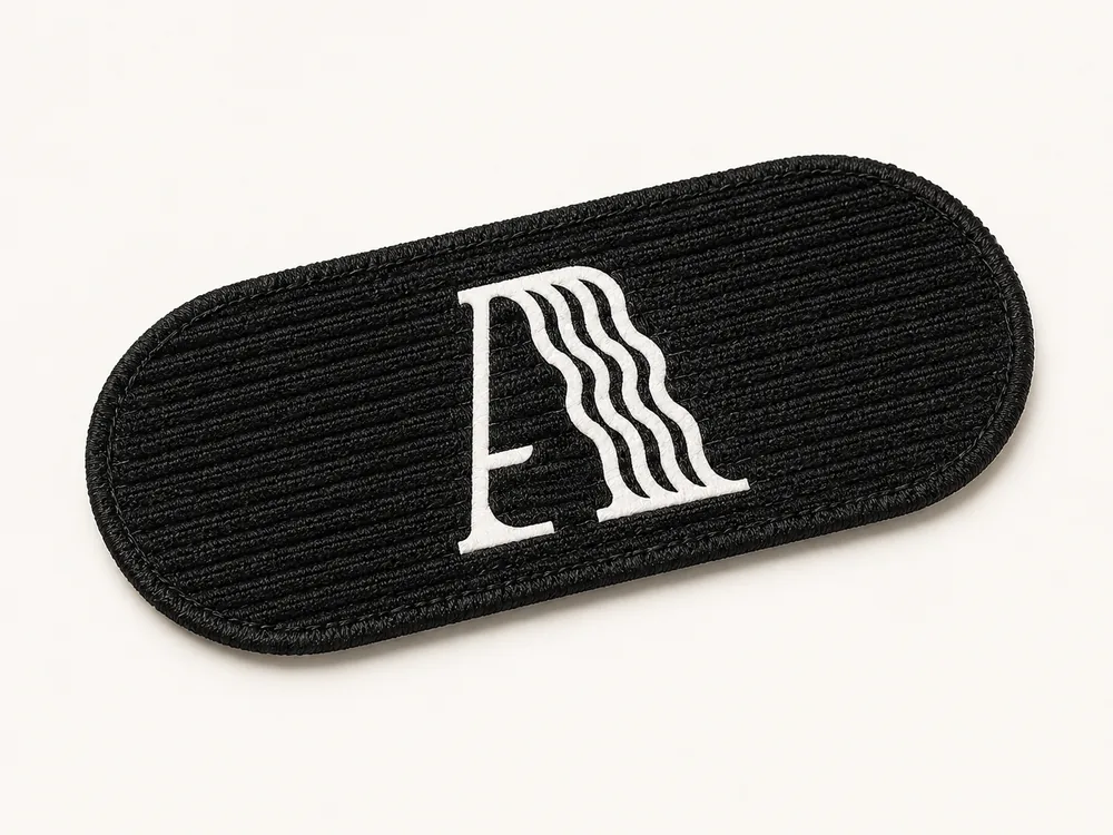 Alpha Hair oval black velcro fastening tab with parallel ridge grip and printed logo for securing bangs and extensions