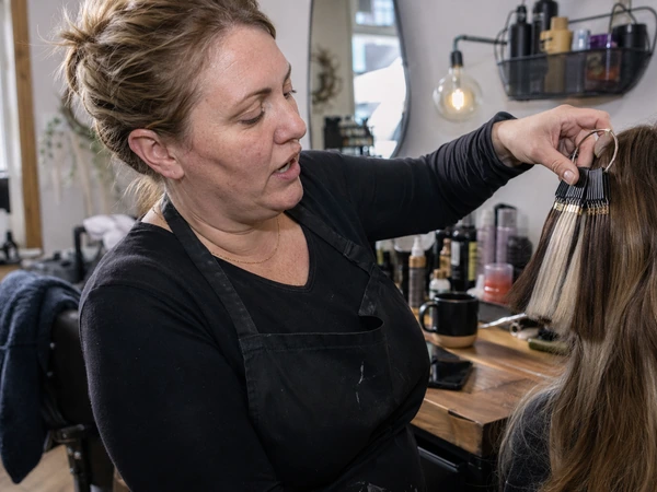 wholesale-salons 55 Salon owner at her two-location UK salon reviewing Alpha Hair Remy hair extension shades by the styling station